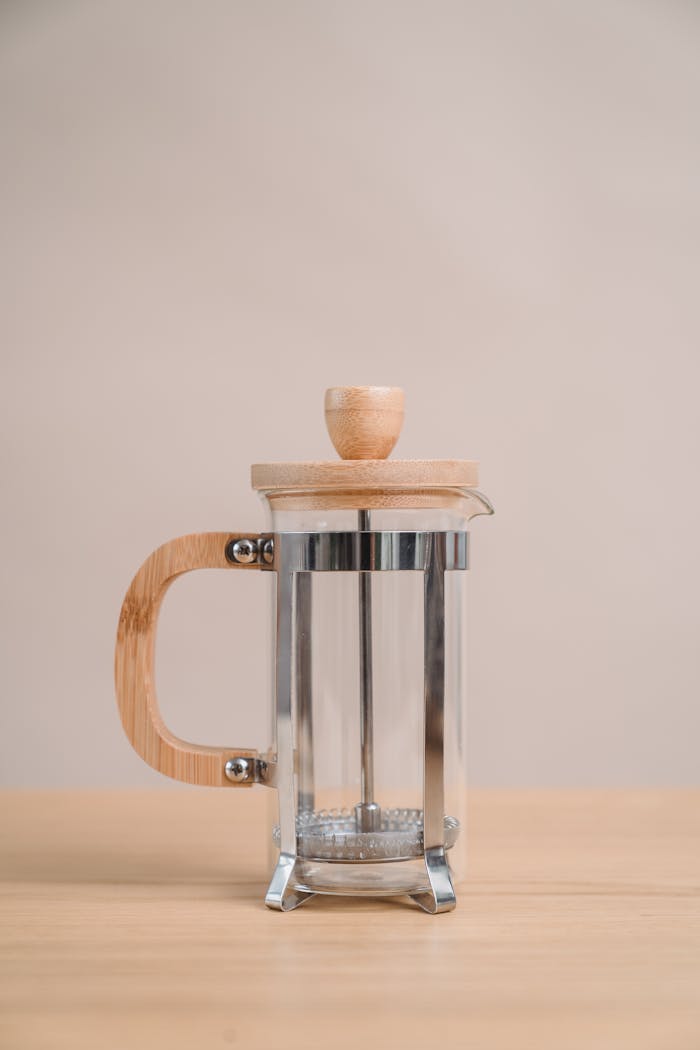 Stylish bamboo and glass French press coffee maker on a wooden table. Ideal for modern kitchens.
